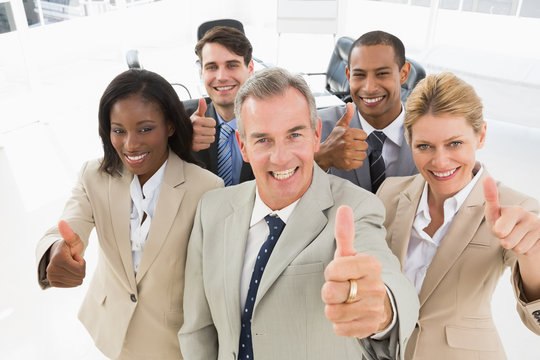 Diverse Close Business Team Smiling Up At Camera Giving Thumbs U