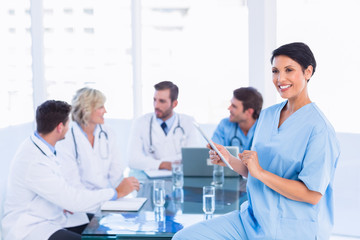 Fototapeta premium Female surgeon using digital tablet with colleagues in meeting