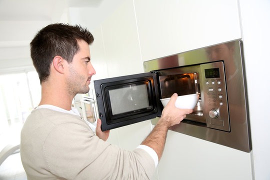 Man Heating Food In Microwave