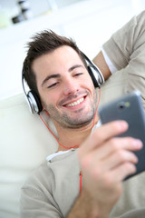 Young man relaxing in sofa with headphones on