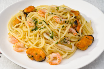 Close up of spaghetti with mussels, shrimps and squid, in a white plate
