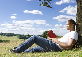 Close up of a man reading a book under the shade of a tree