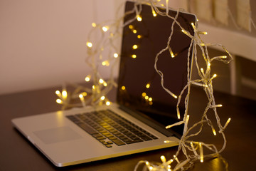 Laptop with garland, on office interior background