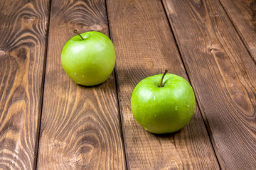 Two green apples on a wooden background
