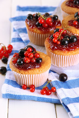 Tasty muffins with berries on white wooden table
