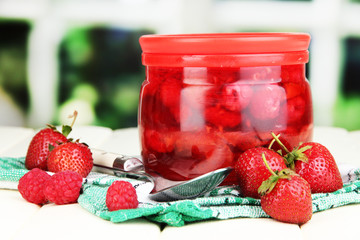 Home made berry jam on wooden table on window background