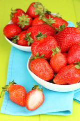Fresh strawberry in bowl on green wooden background