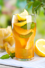 Iced tea with lemon and mint on wooden table, outdoors