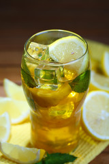 Iced tea with lemon and mint on wooden table