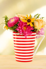 Beautiful bouquet of bright flowers in color mug,