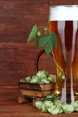 Glass of beer and hops, on wooden table