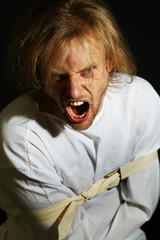 Mentally ill man in strait-jacket on black background