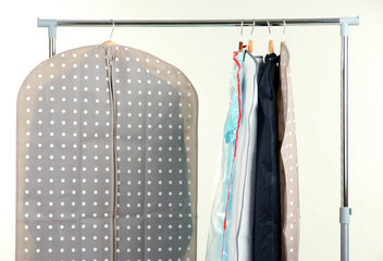 Clothes in cases for storing on hangers, on gray background