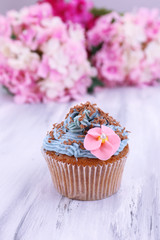 Tasty cupcake with butter cream, on color wooden background