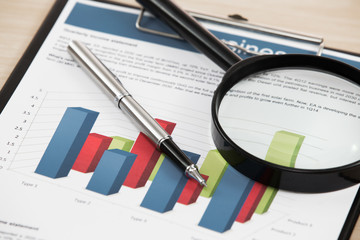 magnifying glass and pen over graph