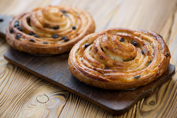 Two spiral sweet buns on a rustic cutting board, horizontal shot
