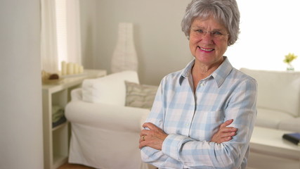 Old woman smiling and standing in living room - Powered by Adobe