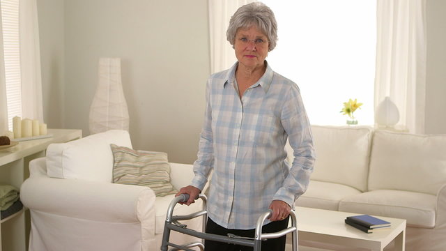 Old woman standing in room with walker