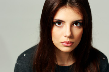 Closeup portrait of a young surprised woman on gray background