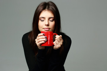 Young happy woman smelling the aroma of coffee