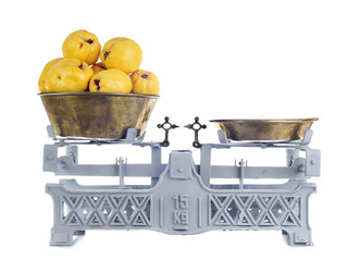 Old-fashioned balance scale with quinces isolated on white