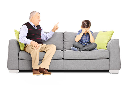 Angry grandfather shouting at his nephew, seated on a sofa