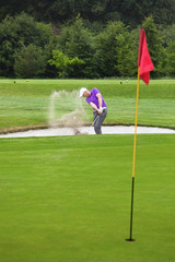 Fototapeta premium Golfer playing out of a bunker