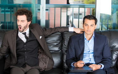 Closeup portrait of two businessman sitting on black couch waiting to talk someone important or an...