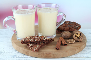 Cups of eggnog with cinnamon and cookies