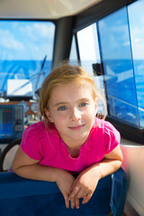 Blond kid girl at boat indoor sailing smiling happy