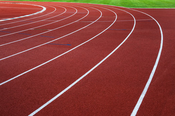 White lines on red running track with green grass.