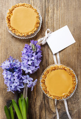 Toffee tarts on wooden table, violet hyacinth flower in the back