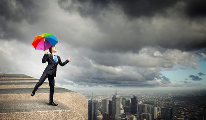 Businessman with umbrella atop of building