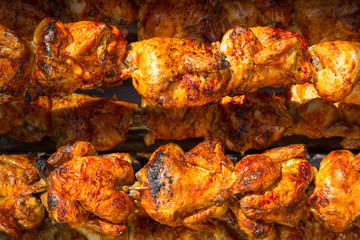 Roasted chicken in a row turning on a roaster