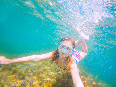 snorkeling blond kid girl underwater goggles and swimsuit