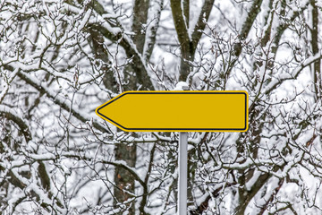 plain yellow arrow sign in the snow pointing left