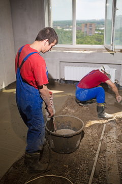 Two workers in a room poured concrete floor