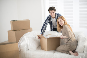 smiling couple leaning on boxes in new home