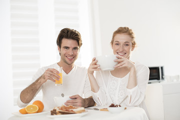 young couple takes breakfast in kitchen