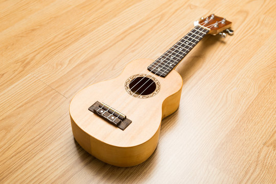 Ukulele over the wooden background