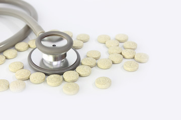 Stethoscope and antibiotic pills on white background