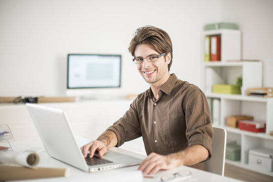 portrait of a smiling man in front of a laptop