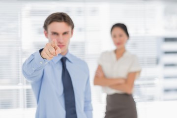 Businessman pointing towards camera with woman in office