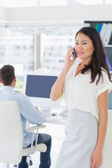 Fototapeta premium Female artist using mobile phone with colleague in background