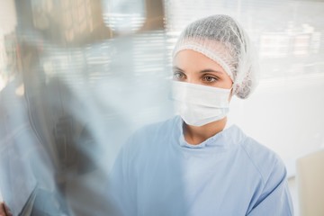 Serious female surgeon examining blurred x-ray