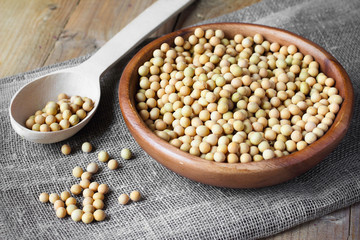 Soybeans in wooden bowl and spoon on linen canvas