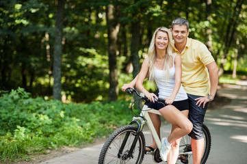 Obraz premium Attractive happy couple on a bicycles in a countryside