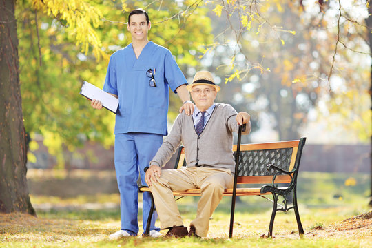 Healthcare professional standing next to a senior man in a park