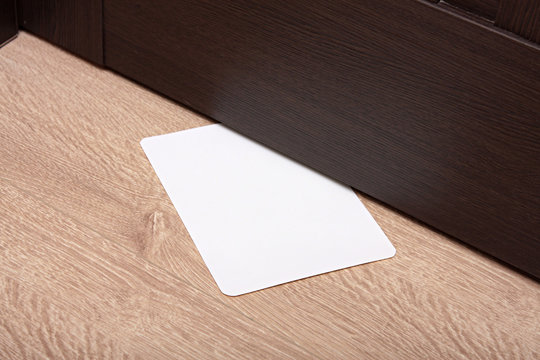 white envelope with message slipped under wooden door. Blank