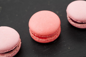Pink macaroons in a row on black background